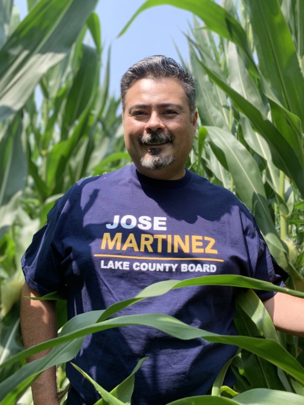 Jose Martinez in a cornfield at a local farm wearing a Lake County Board campaign shirt