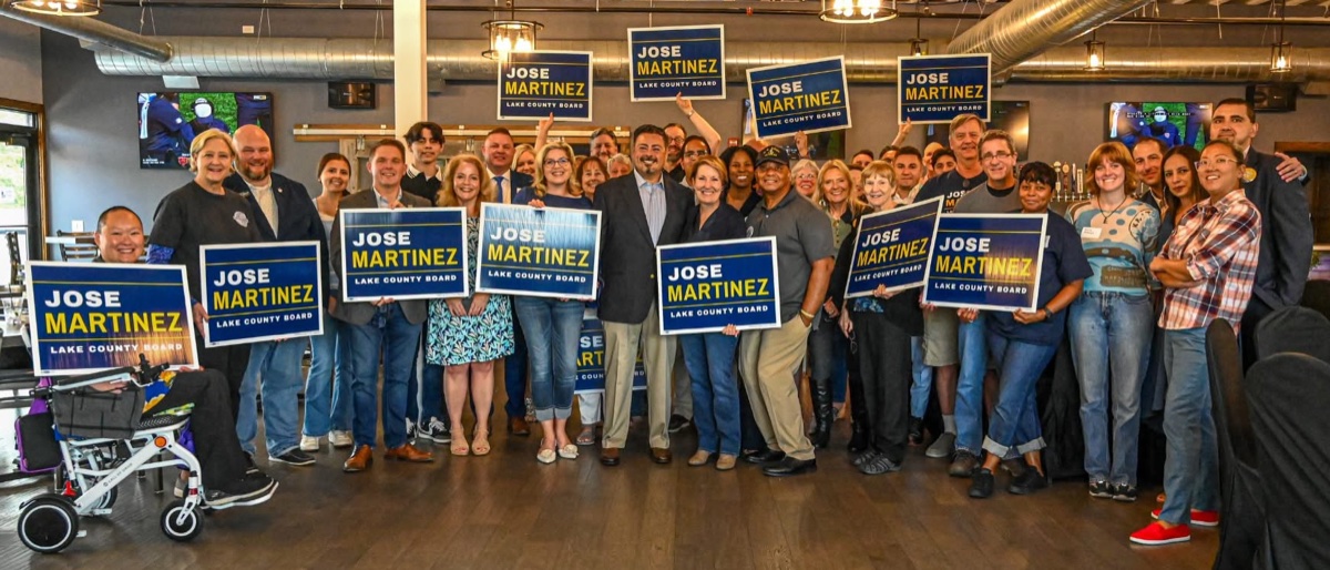 Jose Martinez with a crowd of supporters holding Jose Martinez Lake County Board signs at his campaign fundraiser